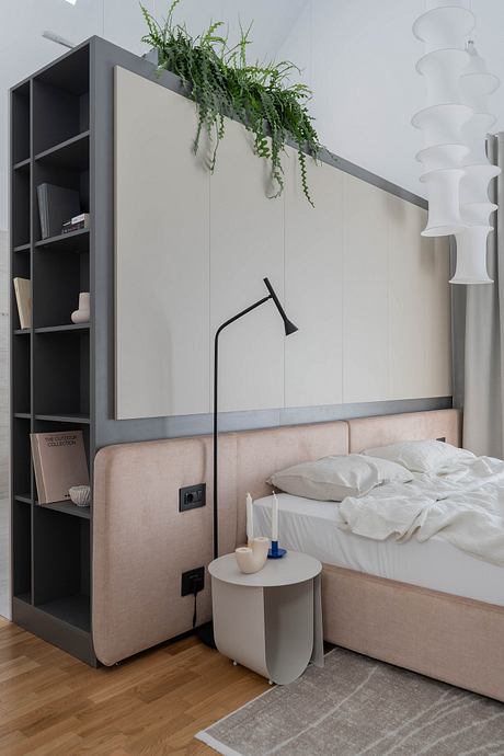 Modern bedroom with sleek gray shelving, hanging plants, and a cozy upholstered bed.