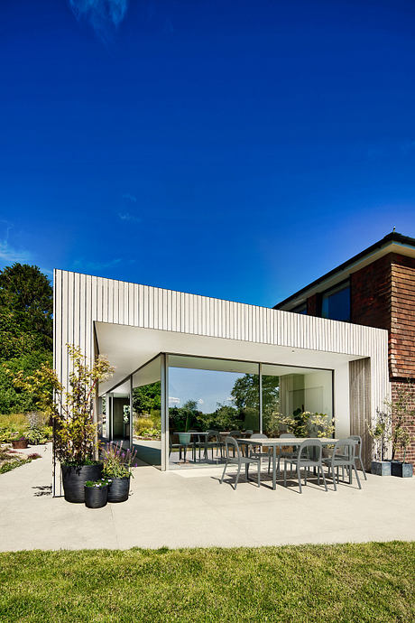 A modern home with a glass-enclosed patio, brick exterior, and lush landscaping.