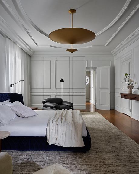 Elegant bedroom with layered lighting, built-in cabinetry, and a striking suspended light fixture.