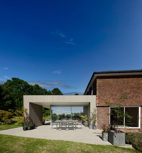 Brick building with a large glass patio, surrounded by a well-manicured lawn and trees.
