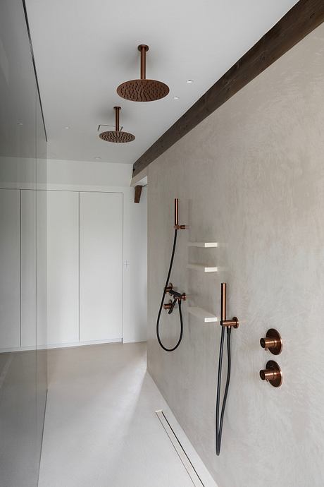 Minimalist bathroom with copper fixtures, dual rain shower heads, and built-in storage.