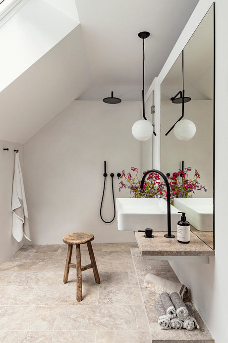 Sleek and modern bathroom with minimalist lighting, stone vanity, and decorative flowers.