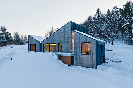 Contemporary mountain cabin with clean lines, wood and metal exterior, and large windows.
