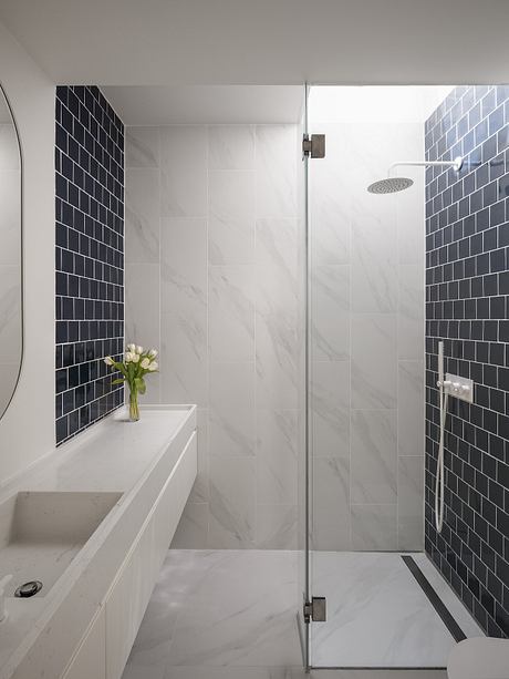Sleek, minimalist bathroom with black subway tile accents and a glass shower enclosure.