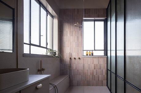 Modern bathroom with large windows, tiled walls, and shower area with showerhead.