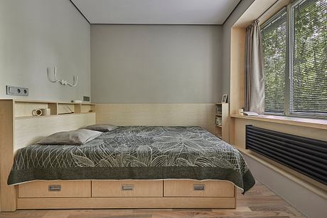 Minimalist bedroom with wooden built-in platform bed, neutral color scheme, and natural light.