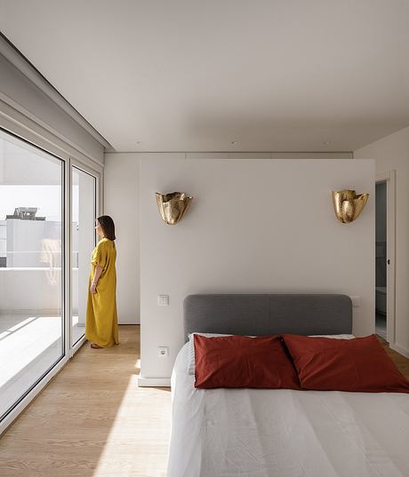 A modern, minimalist bedroom with sleek furnishings, natural lighting, and metallic accents.