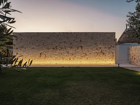 Rustic stone wall casting a warm, golden glow against the tranquil, grassy setting.