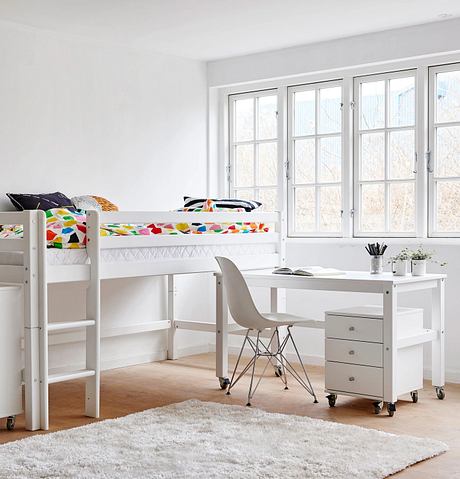 Bright, modern bedroom with large windows, minimalist furniture, and colorful bedding.