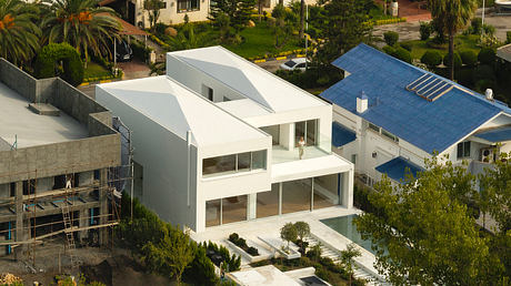 Sleek, geometric white building with expansive glass windows overlooking lush greenery.