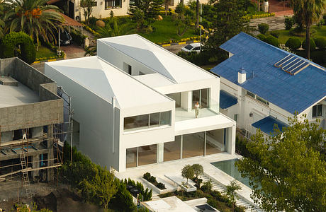 Sleek, geometric white building with expansive glass windows overlooking lush greenery.