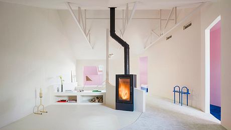 Minimalist, modern living space with wood-burning stove, white walls, and geometric accents.