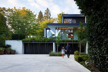 Modern two-story home with sleek black exterior, ample glazed surfaces, and lush landscaping.