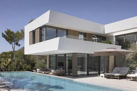 A modern, sleek villa with minimalist architecture, large glass windows, and a pool.