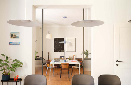 Minimalist dining area with large pendant lights, abstract art, and natural plant accents.