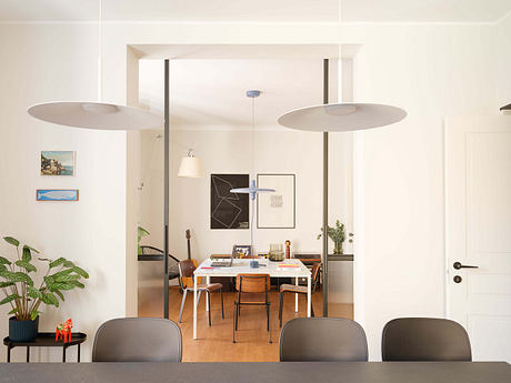 Minimalist dining area with large pendant lights, abstract art, and natural plant accents.