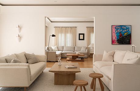 Spacious, minimalist living room with neutral tones, wooden accents, and a vibrant artwork.