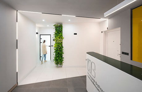 A modern, minimalist lobby with a vertical garden feature and sleek reception desk.