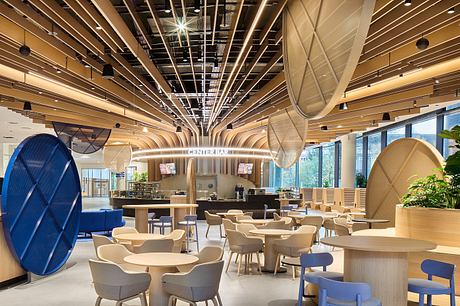 A modern, open-concept cafe with geometric lighting fixtures, wooden furniture, and hints of blue accents.