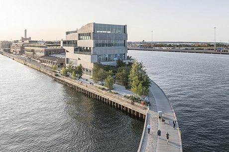 Modern architecture along the waterfront, featuring a multi-story glass and concrete building.