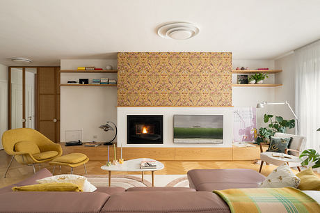 Warm, cozy living room with patterned wallpaper, built-in shelves, and a fireplace.