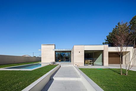 Sleek, modern architecture with glass walls, pool, and lush greenery surrounding the home.