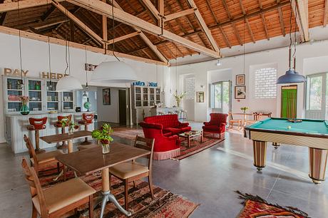 Spacious living room with wooden beam ceiling, red couches, and a pool table.