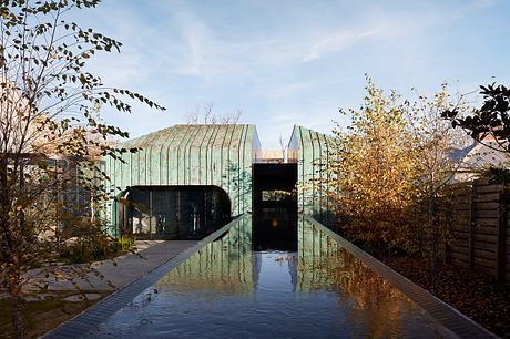 Striking copper-clad building with a reflecting pool and autumn foliage surroundings.