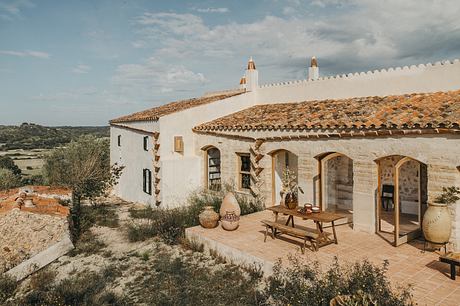 A rustic Spanish-style villa with a tiled roof, arched windows, and a welcoming outdoor patio.