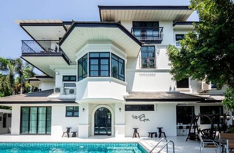 A modern, two-story villa with a glass-enclosed entryway, balconies, and a pool.