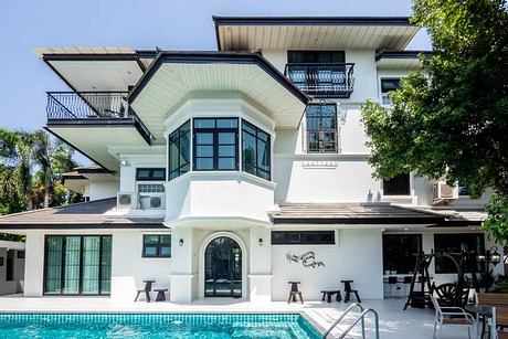 A modern, two-story villa with a glass-enclosed entryway, balconies, and a pool.