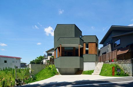 Modern multi-level home with geometric form, wood accents, and landscaped yard.