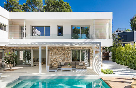 Modern, open-plan villa with stone facade, covered terraces, and sleek pool area.