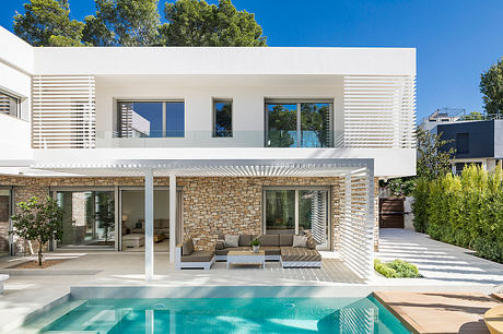 Modern, open-plan villa with stone facade, covered terraces, and sleek pool area.