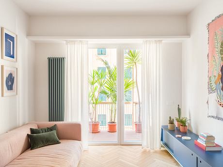 Bright, airy living room with large windows, mid-century modern furniture, and lush indoor plants.