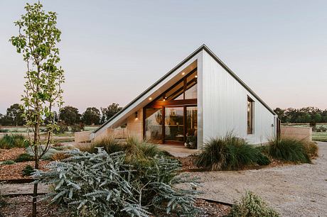 Modern A-frame home with wood accents, large windows, and lush landscaping.