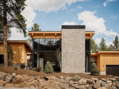 Distinctive stone and wood exterior with tall windows, highlighting natural elements.