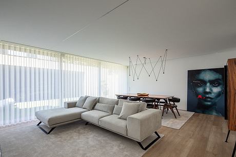 Minimalist living room with large window, sleek sofa, and artistic light fixtures.