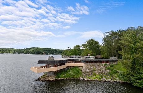 Wooden lakeside structure with stone foundation and surrounding greenery.