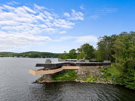 Wooden lakeside structure with stone foundation and surrounding greenery.