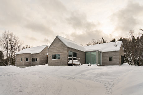 Sophisticated modern wooden cabin with expansive windows overlooking snowy landscape.