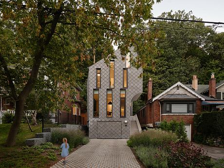 A contemporary home with a striking gray facade, asymmetrical windows, and a welcoming landscaped pathway.