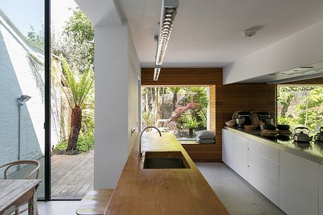 A modern, open-plan kitchen with wooden accents and expansive views of the lush outdoor space.