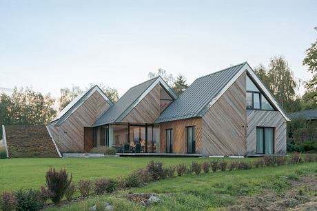 A modern, angular wooden house with prominent roof peaks and large windows offering panoramic views.