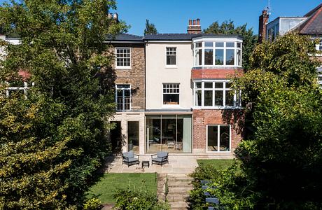 A restored townhouse with a brick and glass extension overlooking a lush garden.