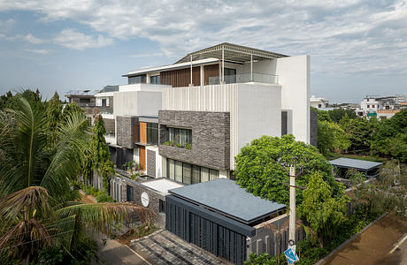 Tropical modern architecture with stone accents, lush greenery, and balconies.