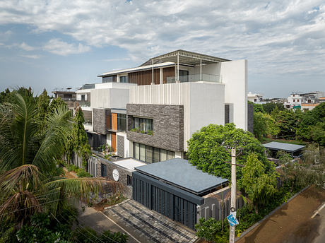 Tropical modern architecture with stone accents, lush greenery, and balconies.