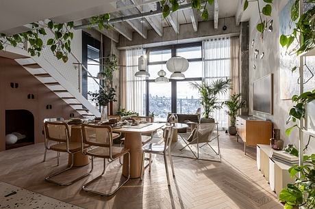 Modern, airy interior with concrete beams, large windows, and lush greenery accents.