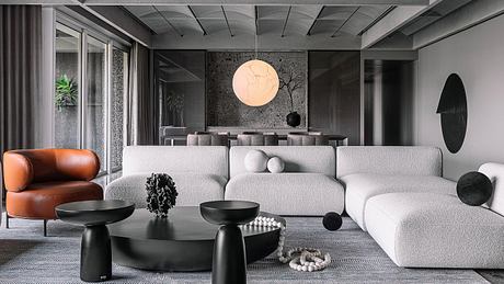 Minimalist living room with modern furniture, circular lighting fixture, and textural elements.