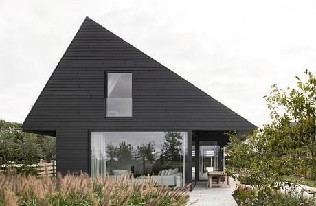 Striking black triangular-roofed structure with expansive glazing and landscaped surroundings.